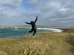Jade Malanczak jumping in the air in a coastal location