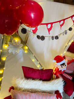a stuffed elf in a santa hat sits in a teepee