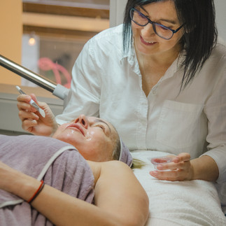 Skincare therapist applying a facial treatment to a client in a cozy salon setting.