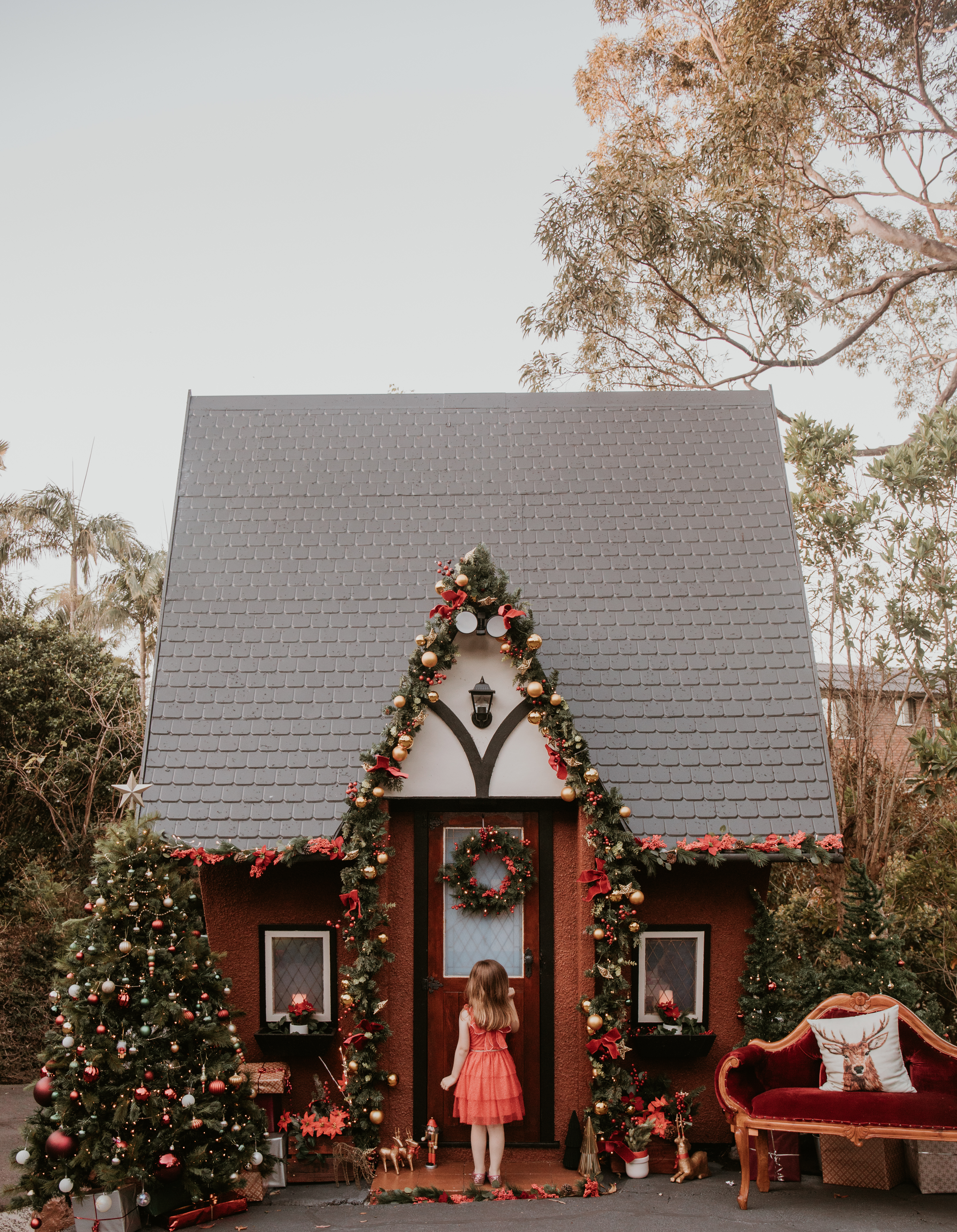 Two children exploring the decorated doorway of Wollongong's Christmas Cottage during a festive photo session.