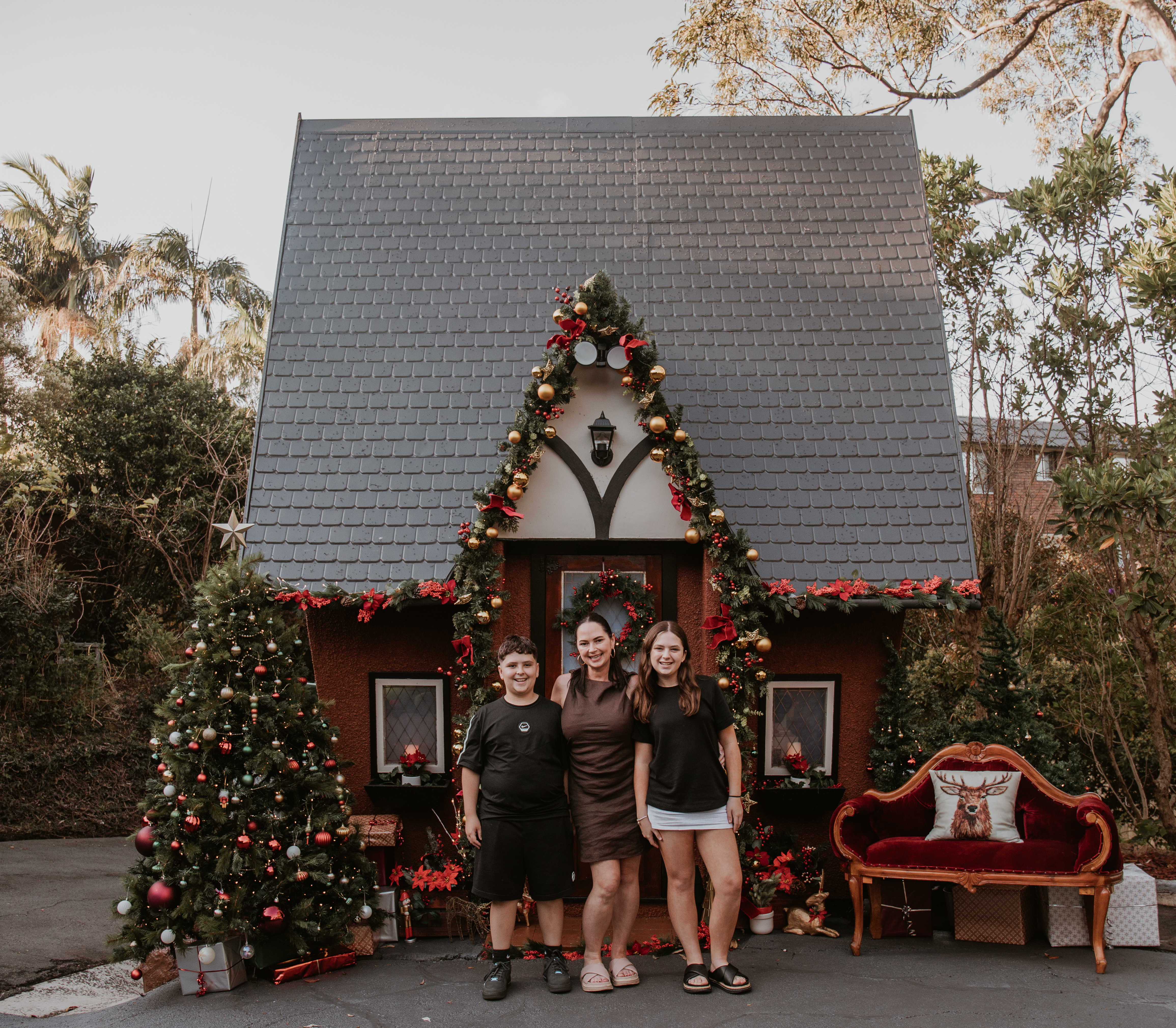 Family enjoying an outdoor Christmas mini photography session in front of a beautifully decorated cottage in Wollongong.