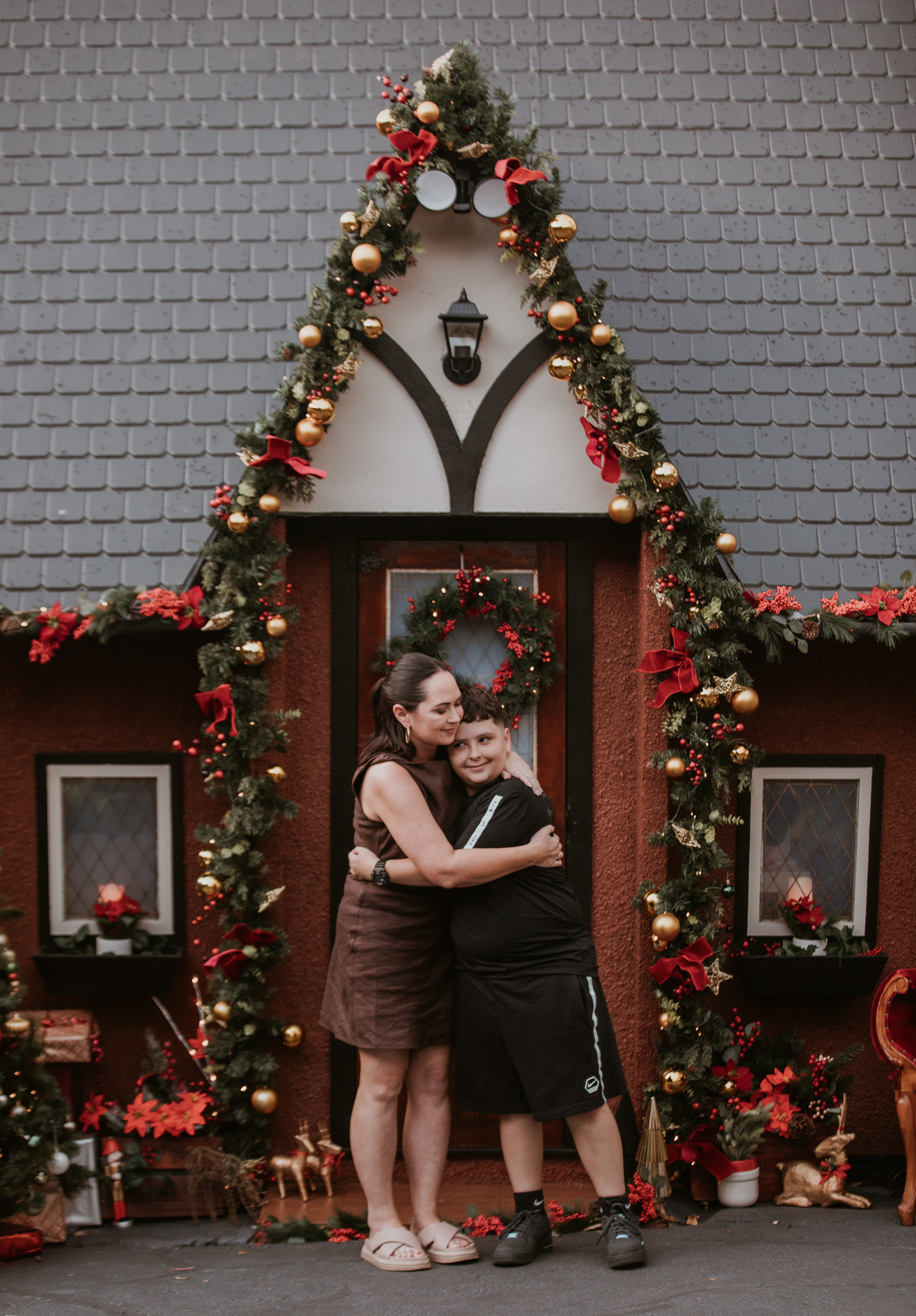 Mother smiling as her two children kiss her cheeks during a relaxed Christmas family photography session.