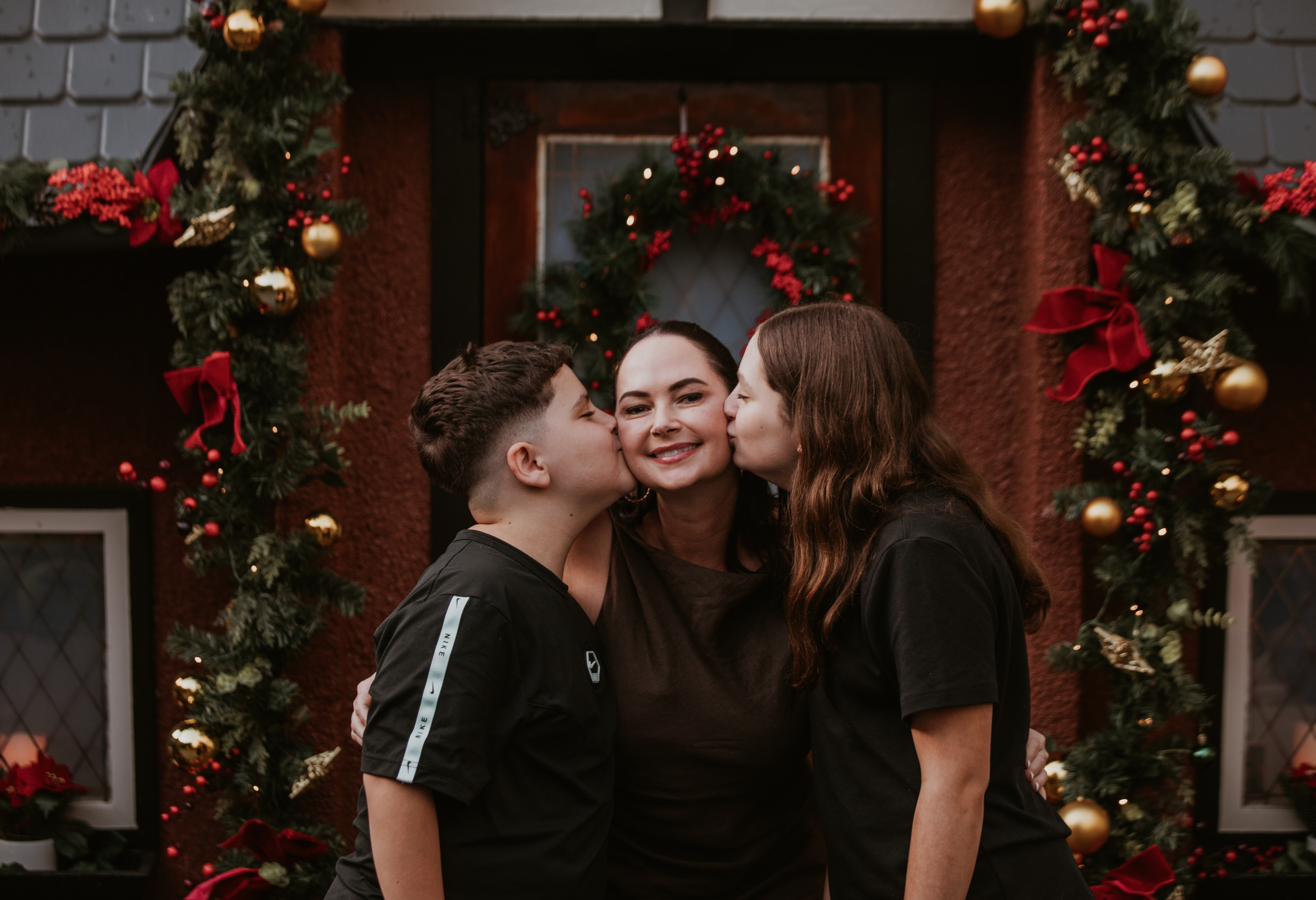 Cottage, featuring children in front of a vintage-inspired Christmas setting. Giving their mother a kiss