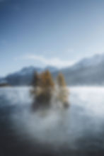 Little island on a beautiful lake with morning fog and mountain background