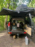 the trunk of a land rover all packed up with camping gear.