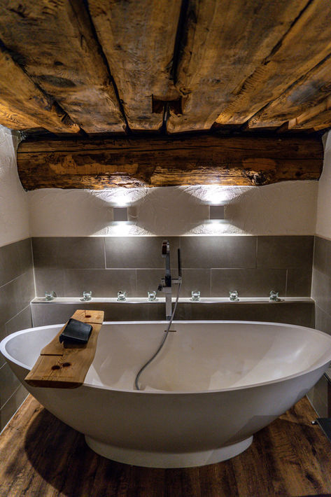 "Elegantes Badezimmer mit freistehender Badewanne und rustikalen Holzelementen im Ferienhaus Haus Rustico in Valposchiavo, ideal für entspannende Momente."