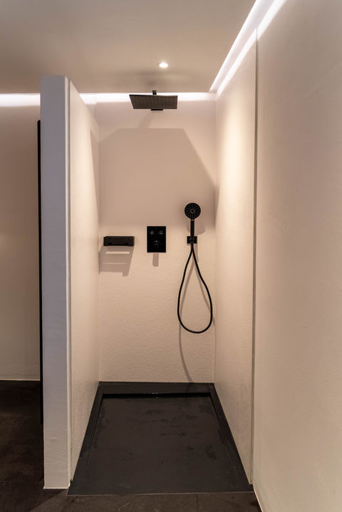 Moderne Dusche in rustikalem Setting mit indirekter Beleuchtung.