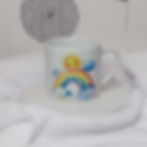 Watercolour rainbow stretching between 2 clouds with a smiling face in the painted sunshine at the top of the rainbow