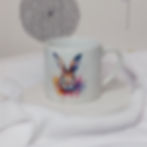 white 6oz ceramic mug with watercolour image of the head of a hare in a cloud of paint drips and splashes