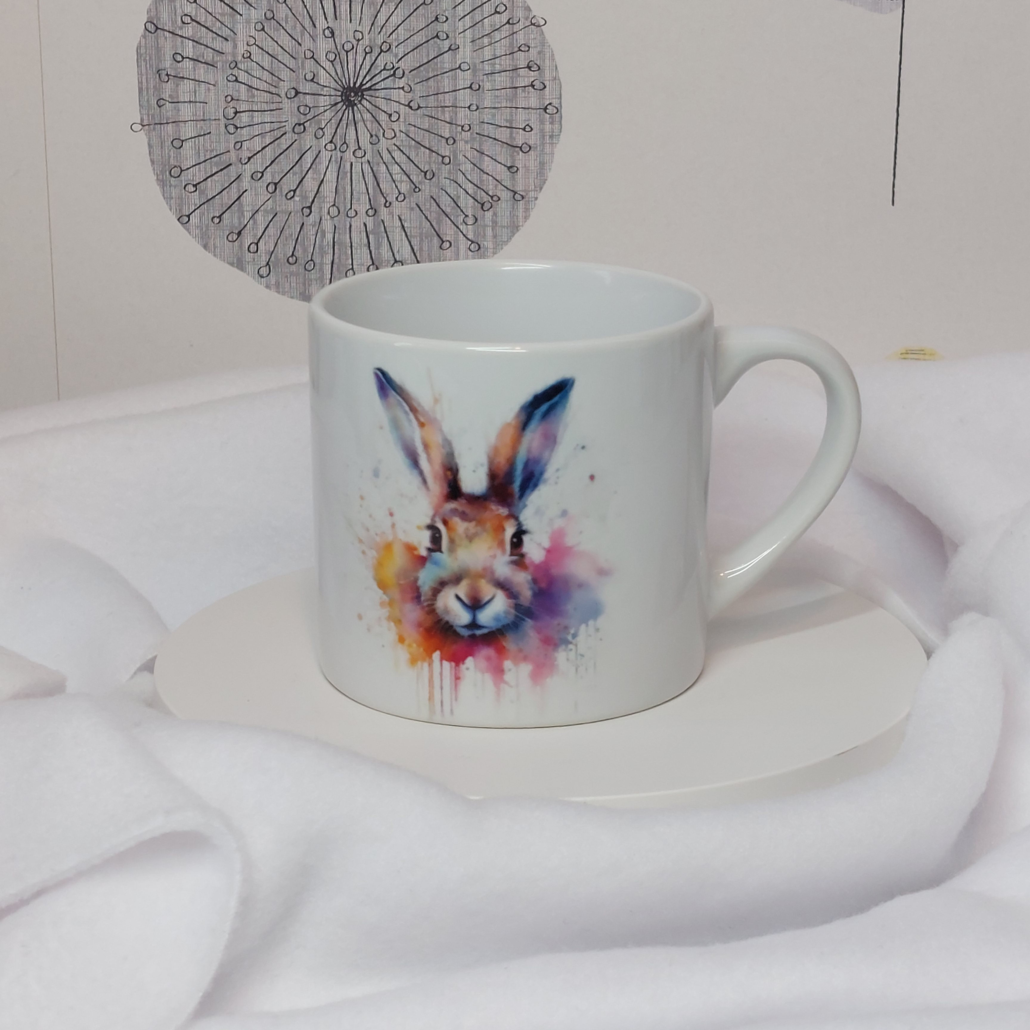 white 6oz ceramic mug with watercolour image of the head of a hare in a cloud of paint drips and splashes