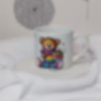 White 6oz ceramic mug with colourful, cute teddy bear in a rainbow jumper with scarf and holding a stack of presents