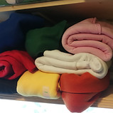 A pile of fleece fabrics in various colours on a shelf