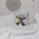 Thumbnail: White 6oz Ceramic Mug with colourful, smiling polar bear in a rainbow snow suit jumping character