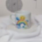 Watercolour rainbow stretching between 2 clouds with a smiling face in the painted sunshine at the top of the rainbow