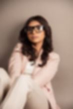 Student studio fashion portrait of a woman wearing oversized glasses and a tailored suit jacket  