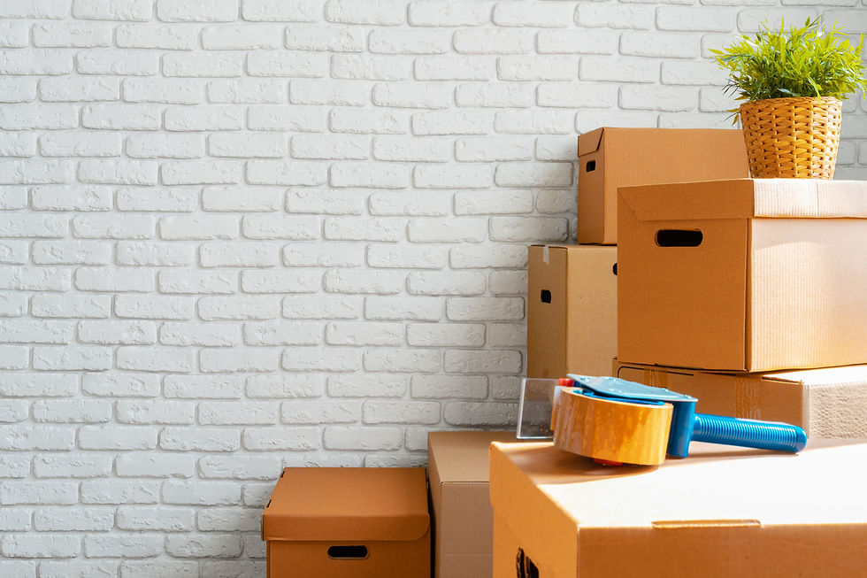 Cardboard removal boxes stacked beside tape dispenser against white brick wall