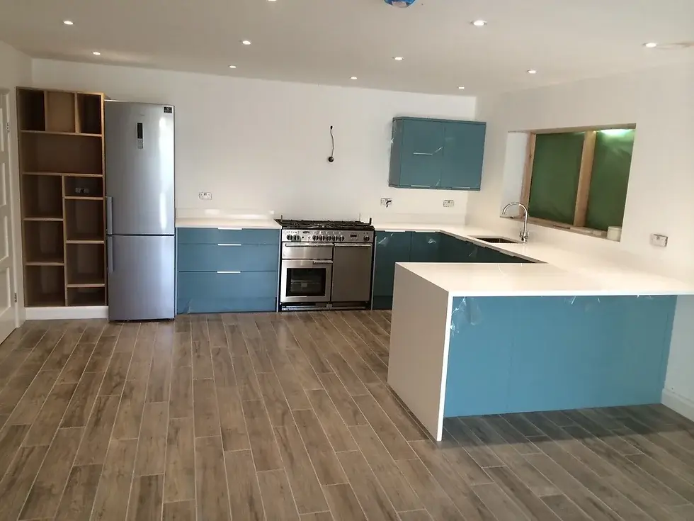 Spacious kitchen with blue cabinets, stainless steel fridge, oven, and wood-effect flooring under bright lighting.