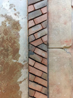 A close-up photo showing a section of brickwork laid out in a herringbone pattern.