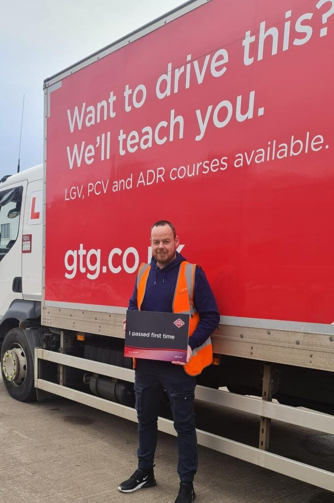 Highlander team member celebrating Class 2 driving licence achievement beside training truck