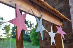 close up of red white and blue wooden star patriotic garland handing from wooden hand rail
