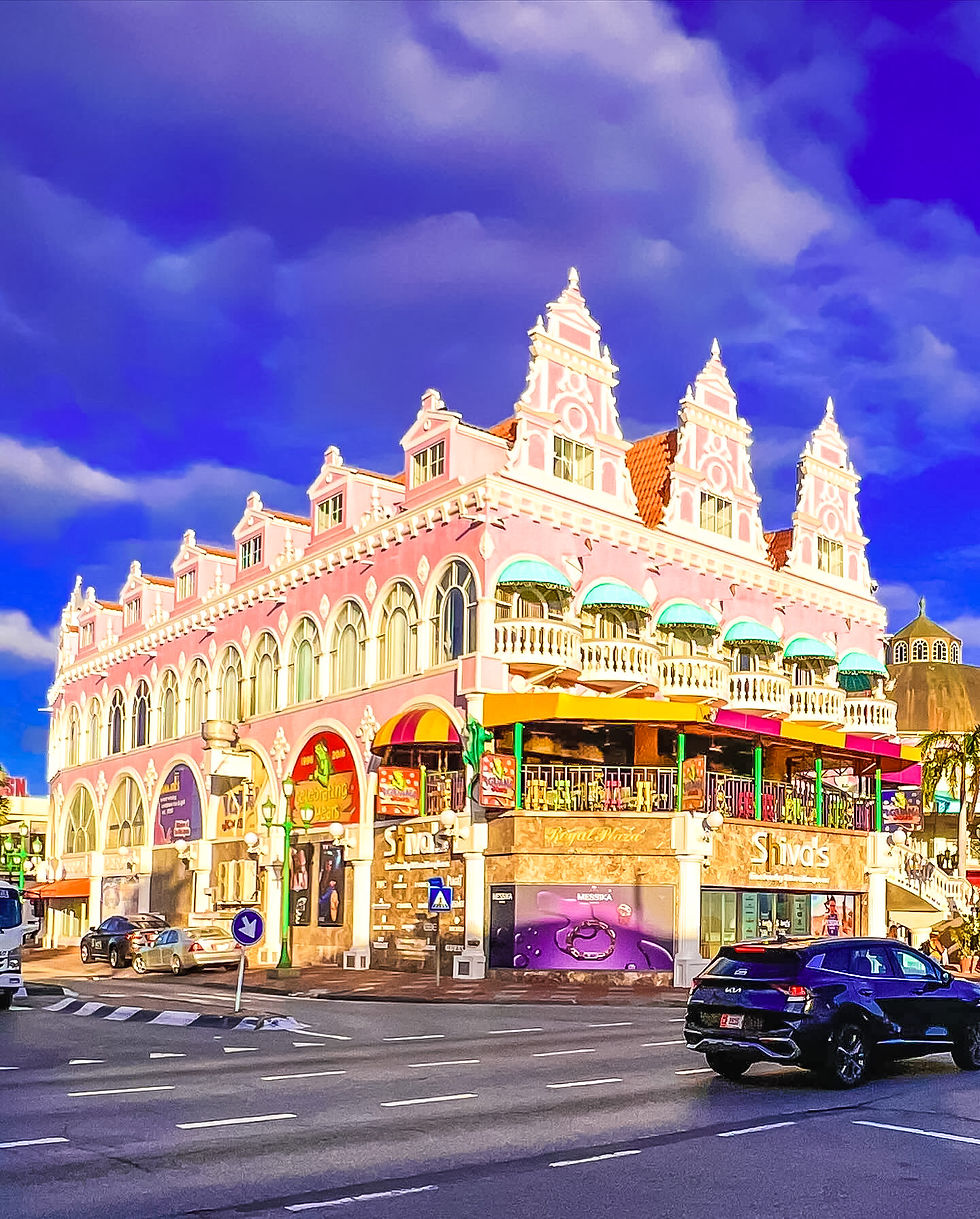 Pink ornate shopping building with Shivas signs, cars on a street, and a dramatic blue cloudy sky above.