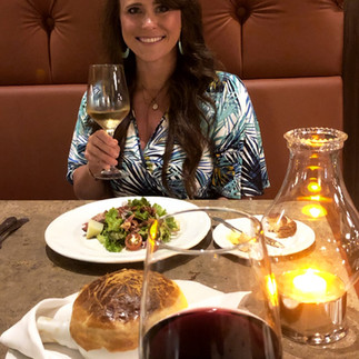 A woman holding a wine glass eating dinner at at La Bastille at Hyatt Ziva Cancun