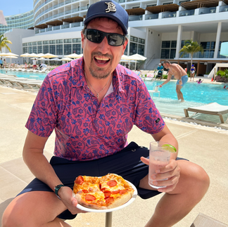 A man smiling about a pizza by a pool