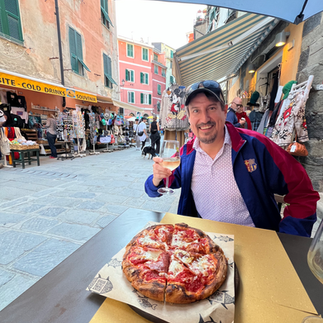 man holding wine glass eating pizza in italy
