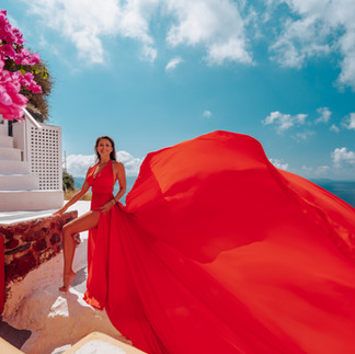 woman on cliff side in flying dress photoshoot in greece