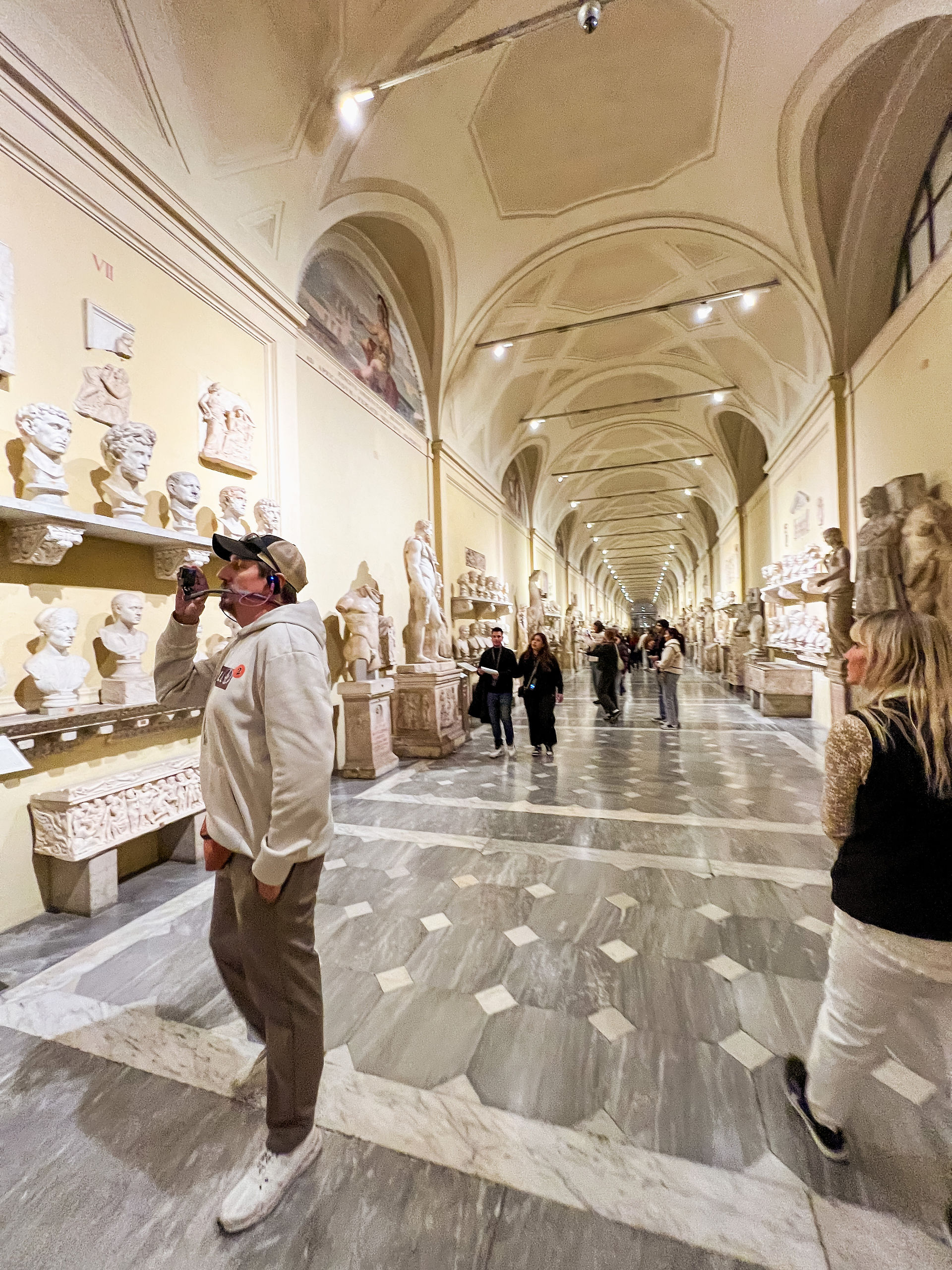 A picture of a man filming ancient busts in the Vatican museum