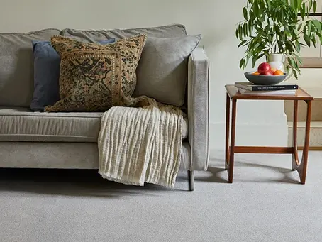 Cosy living room with sofa and soft throw, representing warm carpet flooring for autumn and winter
