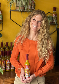 Picture of woman in orange shirt holding a bottle of Jen & Tonics Fire Tonic