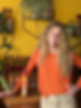Woman in orange shirt standing next to a shelf of Tonic bottles