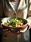A-close-up-shot-shows-a-person-mindfully-holding-a-salad-with-natural-daylight.png