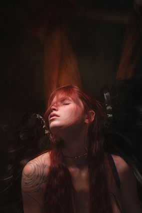 Une jeune femme rousse regardant le ciel représentant la chute d'un ange triste