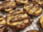 Chocolate-drizzled cookies cooling on a wire rack, golden and glossy brown, close-up of fresh baked treats.