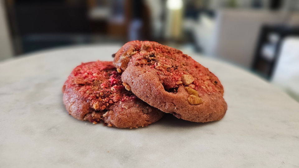 Two delicious cookies with strawberry chunks on white table
