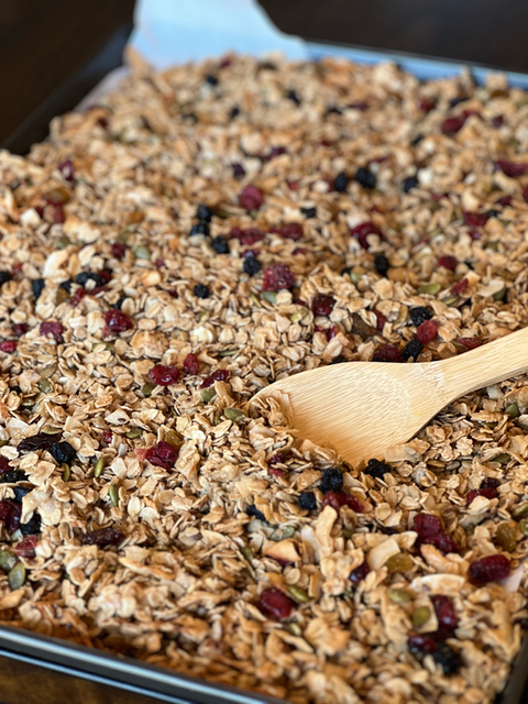 Granola on baking sheet with wooden spoon close up shot. Divine Dough