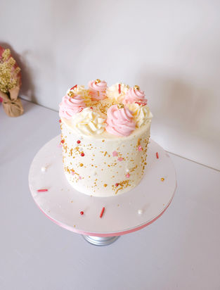 Small round cake with pink and white frosting, sprinkles and Cakes