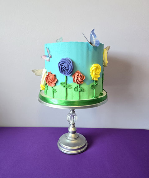 Blue cake with flowers and butterflies Cakes on cake stand Simply Radiant Sweets LLC
