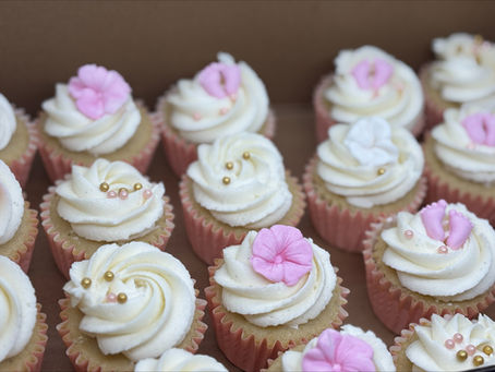 Cupcakes with white icing and pink flowers in a box; The Mixing Belle