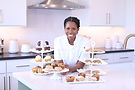 Baker smiling with tiers of cupcakes and pastries