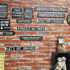 A wall the is full of various quirky cast iron signs 