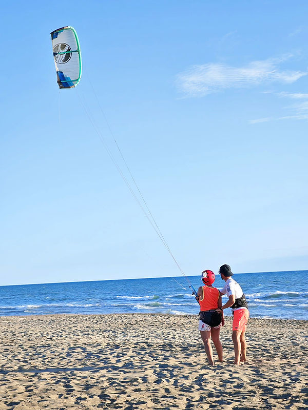 Ll'istruttore kitesurf MAKAI con l'allieva entrambi guardano il kite in alto a Fregene Roma