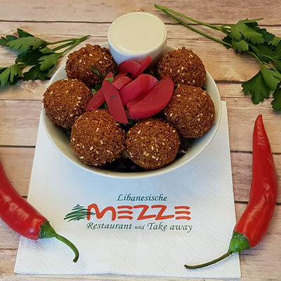 Knusprige Falafel auf einem Teller mit Tahini-Sauce und frischen Kräutern