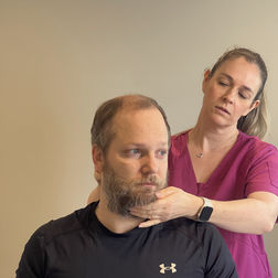 Female therapist adjusting man's neck during a physiotherapy session.