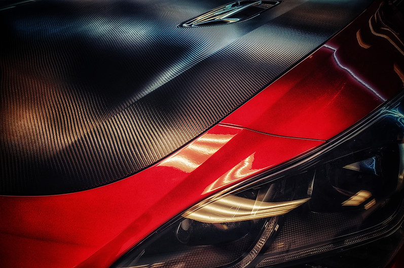 Avery Dennison SW900 Black Textured Carbon Fiber Vinyl Wrap on the hood of a red Kia Stinger.