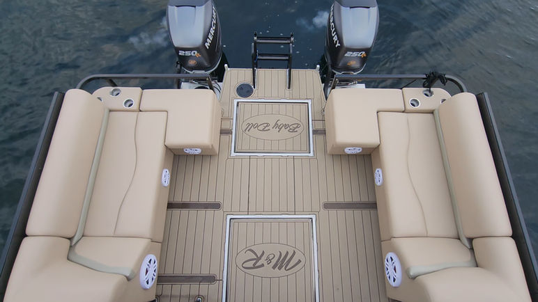 Overhead view of a luxury boat with logo and two engines on water.