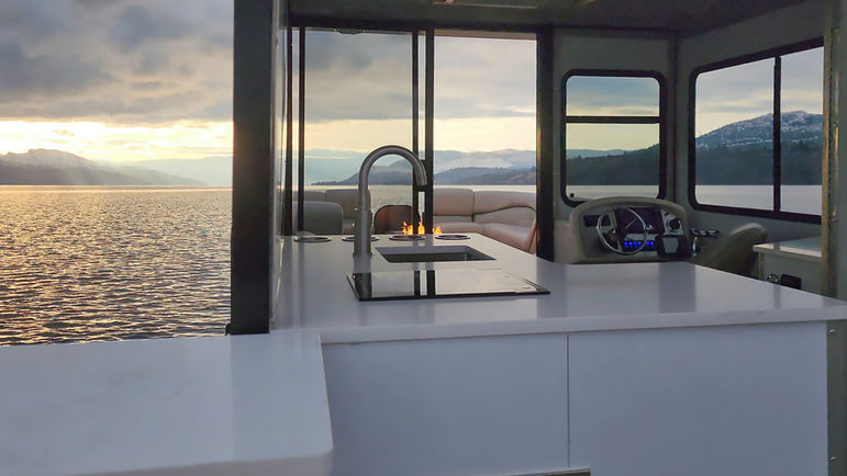 Modern kitchen interior with lake view and mountains during sunset, kelowna luxury boat tours
