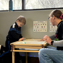 Therapist sitting at a table with a child.